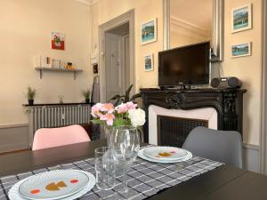 een eetkamer met een tafel met bloemen en een televisie bij Carla's Residences F1 Hyper Centre in Aix-les-Bains