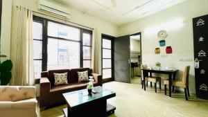 Olive Service Apartments - Medanta Medicity في جورجاون: غرفة معيشة مع أريكة وطاولة