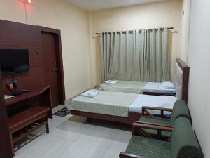 una camera d'albergo con due letti e una televisione di Hotel Orchid a Guwahati