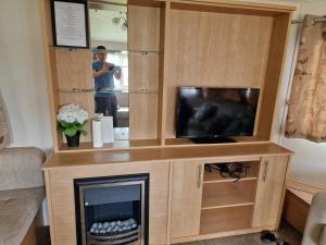 a entertainment center with a tv and a fireplace at Plot 203 paris in Rhyl +8 photos