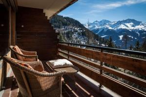 two wicker chairs on a balcony with a view of mountains at Mondzeu E38 in Verbier