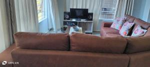 a living room with a brown couch and a tv at Tugela Mouth Sea View Guest House (Sleeps 8) in Tugela Mouth