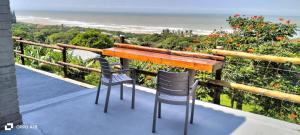 een tafel en 2 stoelen op een balkon met uitzicht op de oceaan bij Tugela Mouth Sea View Guest House (Sleeps 8) in Tugela Mouth