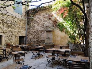 un patio al aire libre con mesas, sillas y una pared de piedra. en LE PATIO, en Grignan