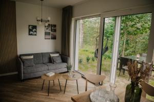 - un salon avec un canapé et une grande fenêtre dans l'établissement Sam Las Apartamenty Białowieża, à Białowieża