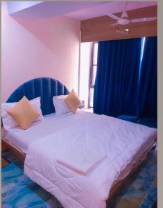 1 dormitorio con 1 cama grande y cortinas azules en hotel shivkunj, en Ahmedabad