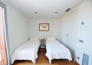 2 camas en una habitación con paredes blancas en Picasso Street, en Vilassar de Mar