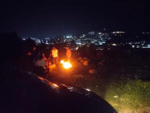 a group of people standing around a fire at night at Seven Endue Delight with Mountain view on the Hill Top in Ooty