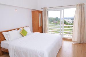 a bedroom with a white bed and a large window at Seven Endue Delight with Mountain view on the Hill Top in Ooty
