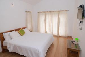 a bedroom with a large white bed and a table at Seven Endue Delight with Mountain view on the Hill Top in Ooty