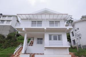 a white house with a solarium on top of it at Seven Endue Delight with Mountain view on the Hill Top in Ooty