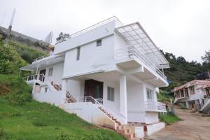 a white house with stairs on a hill at Seven Endue Delight with Mountain view on the Hill Top in Ooty