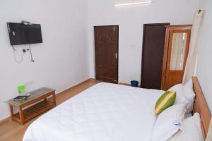 a bedroom with a bed and a tv on the wall at Seven Endue Delight with Mountain view on the Hill Top in Ooty