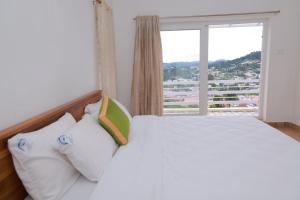 a bedroom with a white bed with a large window at Seven Endue Delight with Mountain view on the Hill Top in Ooty