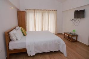 a bedroom with a white bed and a television at Seven Endue Delight with Mountain view on the Hill Top in Ooty