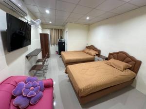 a room with two beds and a couch and a television at Nopphadon Hotel in Lat Krabang