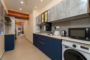 een keuken met blauwe kasten en een wasmachine en droger bij Lumiere Premium Apartments in Trivandrum