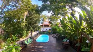 a pool on a wooden deck with chairs and a house at Hotel Natur Campeche in Florianópolis