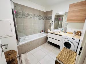 ein Badezimmer mit einer Badewanne und einer Waschmaschine in der Unterkunft JO Paris 2024 in Saint-Ouen