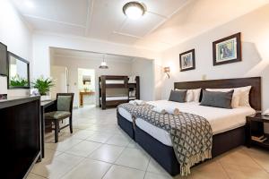 Schlafzimmer mit einem Kingsize-Bett und einem Schreibtisch in der Unterkunft Hotel Numbi & Garden Suites in Hazyview