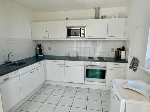 a white kitchen with white cabinets and a microwave at Bohemien Resort 46 in Sint Maartensvlotbrug