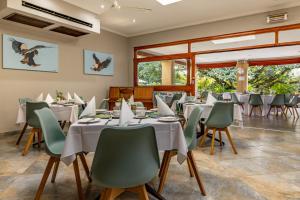ein Esszimmer mit weißen Tischen und grünen Stühlen in der Unterkunft Hotel Numbi & Garden Suites in Hazyview