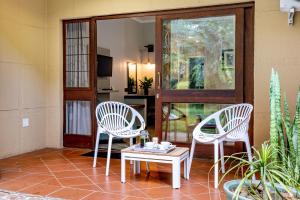 2 sillas blancas y una mesa en una habitación en Hotel Numbi & Garden Suites en Hazyview