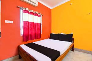 Ce lit se trouve dans un dortoir doté d'un mur orange. dans l'établissement SPOT ON HOTEL MEERa, à Farakka