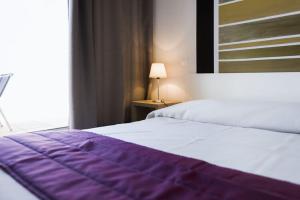 Un dormitorio con una cama morada y blanca y una ventana en R sidence Alba Rossa Serra di Ferro accommodation with terrace or balcony en Serra-di-Ferro