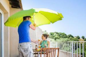 a man and a woman sitting at a table under an umbrella at R sidence Alba Rossa Serra di Ferro accommodation with terrace or balcony in Serra-di-Ferro