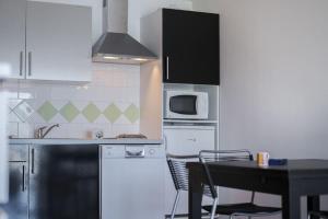 eine Küche mit weißen Schränken, einem Tisch und einer Mikrowelle in der Unterkunft R sidence Alba Rossa Serra di Ferro accommodation with terrace or balcony in Serra-di-Ferro