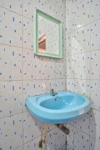 Om Sai Guest House في كالانغيُت: حمام مع حوض أزرق ومرآة