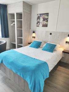 a bedroom with a large bed with blue pillows at Hotel Sfinx in De Panne