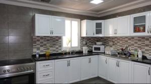 a kitchen with white cabinets and a sink at PRIVATE ROOM WITH WASHROOM AND BALCONY in Dubai