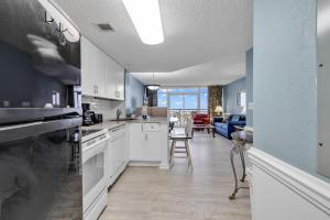 a kitchen with white cabinets and a living room at Atlantica Resort Condo Oceanfront Close to the beach in Myrtle Beach