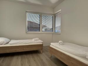 two beds in a room with two windows at 33 Apartments in Orechová Potôň