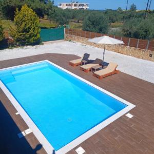 a blue swimming pool with two chairs and an umbrella at Drosoula Villa 3bdr private swimming pool in Chorafakia