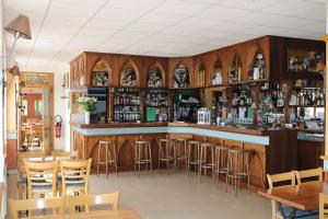 eine Bar mit Holzschränken und Barhockern in der Unterkunft Le Grand Connétable in Châteauneuf-de-Randon