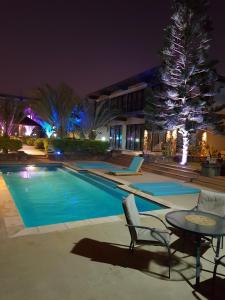 Villas Rocher - Junior Suite 2C في غراند بايَ: مسبح في الليل مع طاولة وكراسي