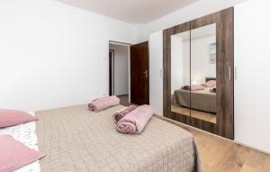a bedroom with two beds with pink pillows and a mirror at Apartman Nora in Mučići