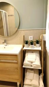 een badkamer met een wastafel, een spiegel en handdoeken bij Sweet Aviles Apartamento in Avilés