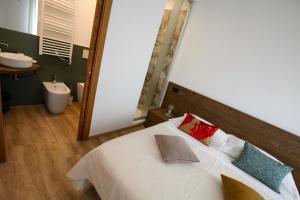 a bedroom with a large white bed and a bathroom at La Giuggiola in Arquà Petrarca