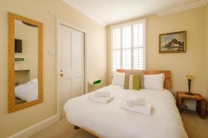 una camera da letto con un grande letto bianco e uno specchio di Tanyard House a Woodbridge