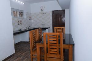 a kitchen with wooden chairs and a black table at Seven Endue Delight with Mountain view on the Hill Top in Ooty