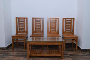 three wooden chairs and a table with a glass top at Seven Endue Delight with Mountain view on the Hill Top in Ooty