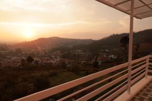 a view of the sunset from the balcony of a house at Seven Endue Delight with Mountain view on the Hill Top in Ooty