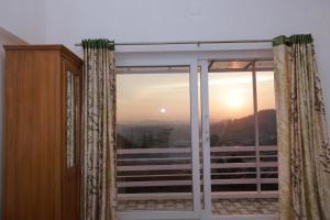 a window with a view of the sunset at Seven Endue Delight with Mountain view on the Hill Top in Ooty