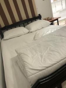 ein Bett mit weißer Bettwäsche und Kissen darauf in der Unterkunft cozy room near the airport in Kairo