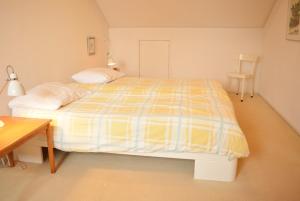 a bedroom with a yellow and white bed and a table at DU121 - spacious apartment in the centre in Domburg