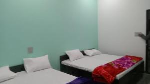 2 Einzelbetten in einem Zimmer mit weißen Wänden in der Unterkunft Shree Banke bihari home stay in Mathura